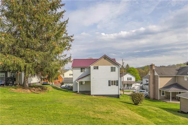 a view of a house with a big yard and large trees