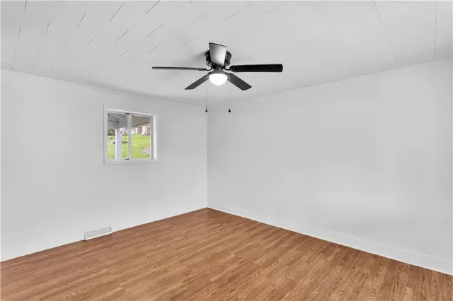 a view of empty room with wooden floor and ceiling fan