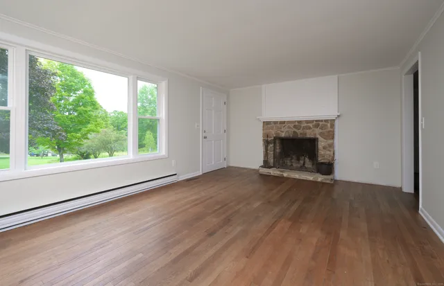 an empty room with wooden floor fireplace and windows