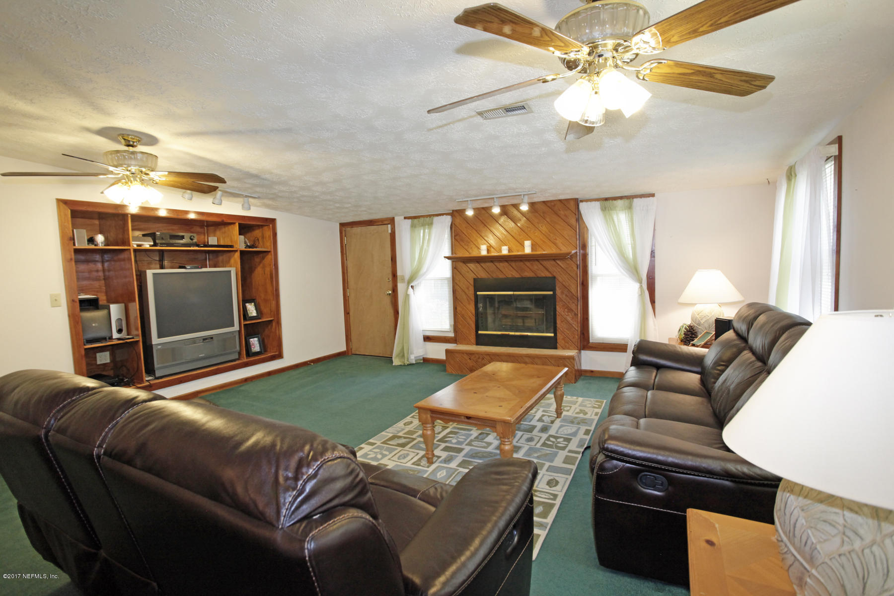 4956 Spring Glen Road Jacksonville, FL 32207 - Photo 12 of 23 a living room with furniture a fireplace and a flat screen tv