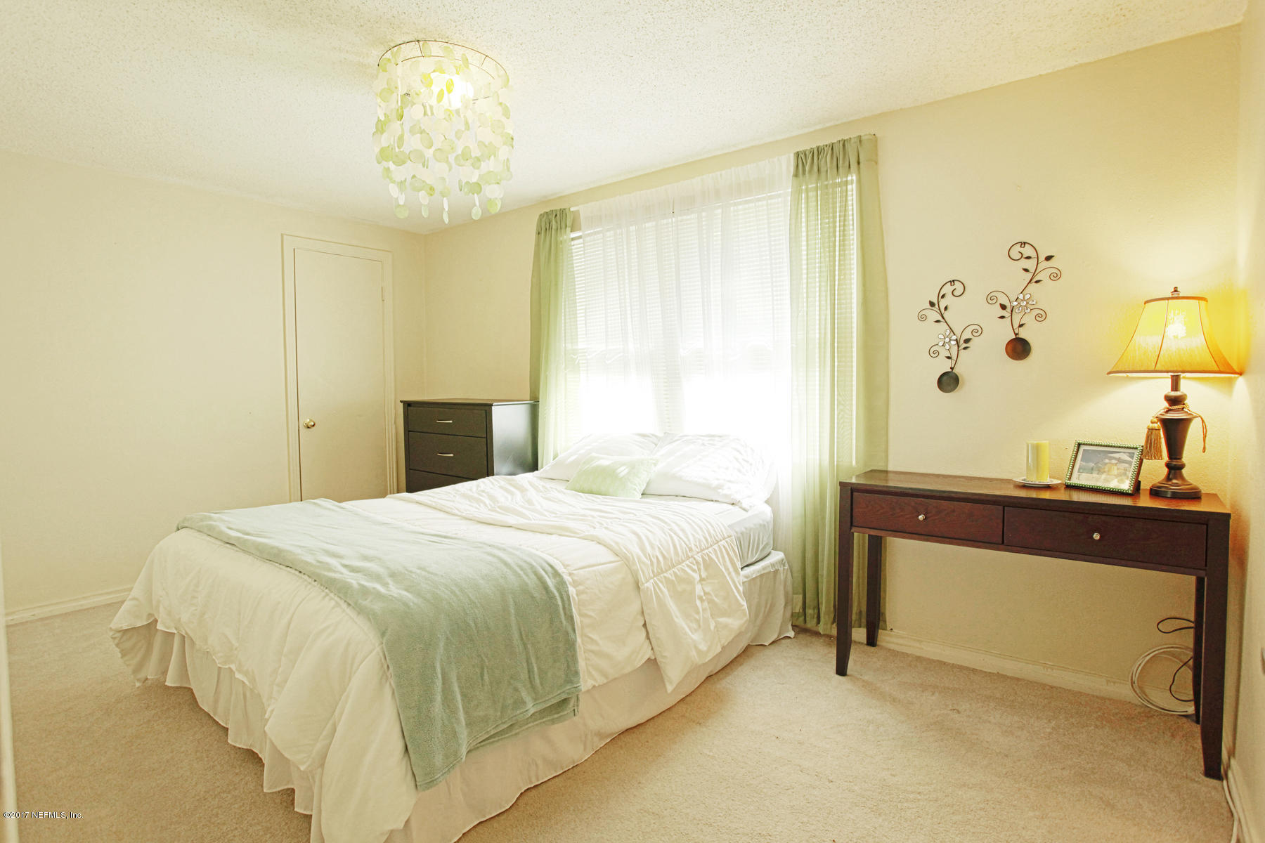 4956 Spring Glen Road Jacksonville, FL 32207 - Photo 17 of 23 a bedroom with a bed and a chandelier