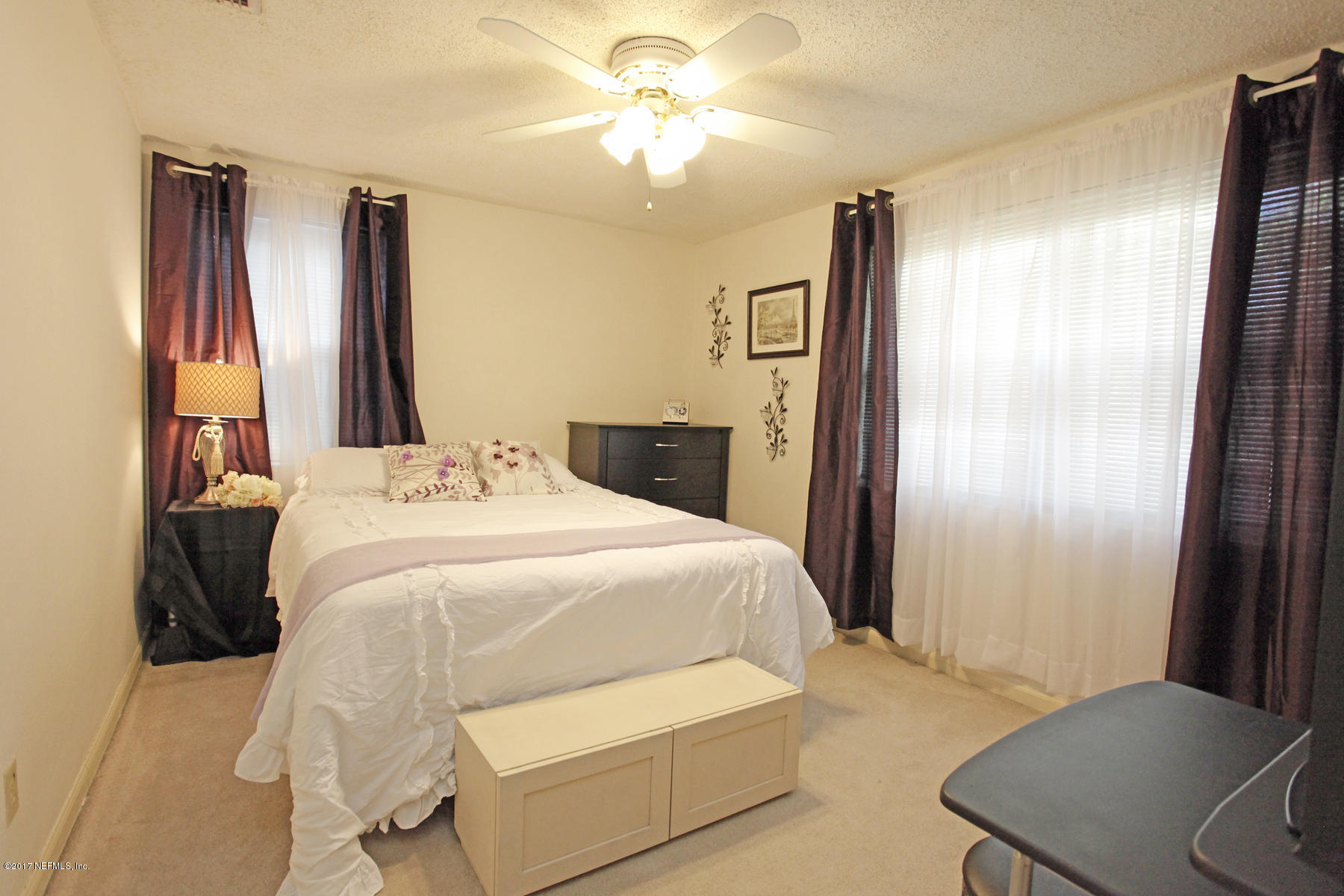 4956 Spring Glen Road Jacksonville, FL 32207 - Photo 18 of 23 a bedroom with a bed and a chandelier