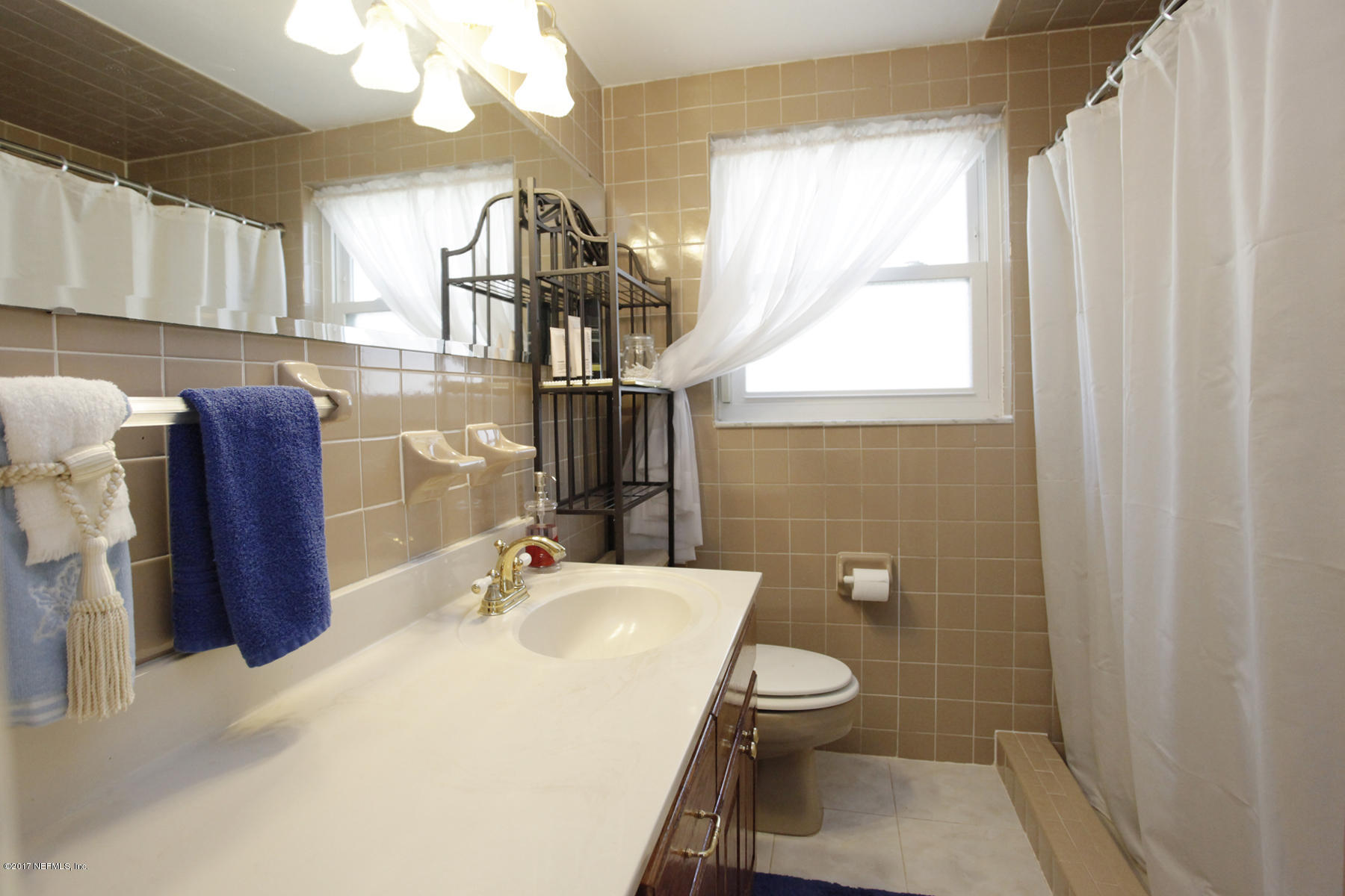 4956 Spring Glen Road Jacksonville, FL 32207 - Photo 19 of 23 a bathroom with a sink a toilet and mirror