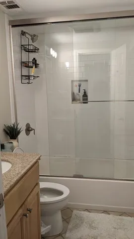 a bathroom with a granite countertop sink a toilet and shower