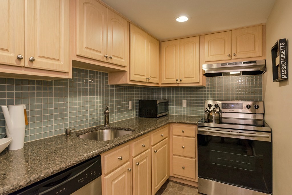 390 Riverway, Unit 1 Boston, MA 02115 - Photo 5 of 12 a kitchen with stainless steel appliances granite countertop a sink a stove and cabinets