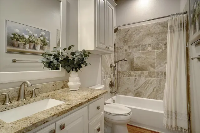 a bathroom with a granite countertop sink toilet and shower