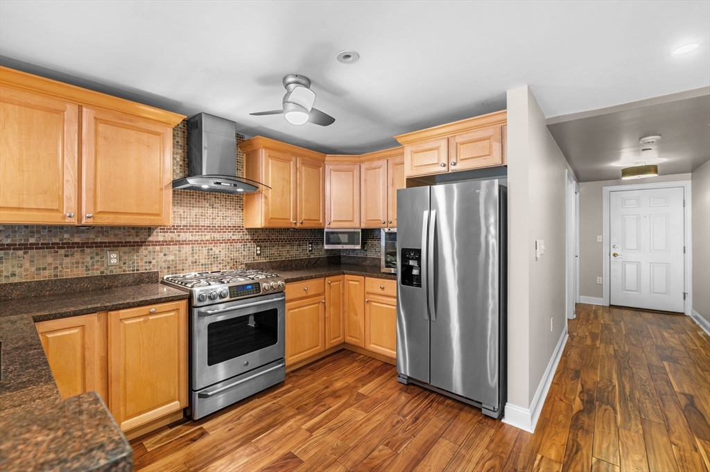 60 Merrimac Street, Unit 604 Amesbury, MA 01913 - Photo 13 of 42 a kitchen with stainless steel appliances granite countertop a refrigerator a sink dishwasher a stove and white countertops with wooden floor