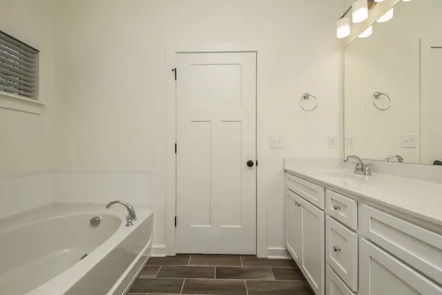 a bathroom with a tub sink shower and two mirror