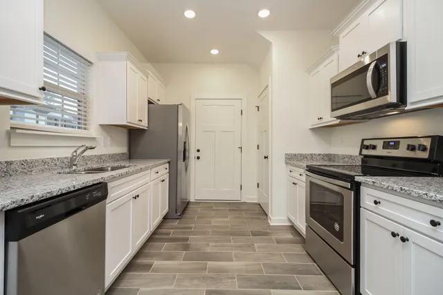a kitchen with stainless steel appliances granite countertop a stove top oven microwave and refrigerator