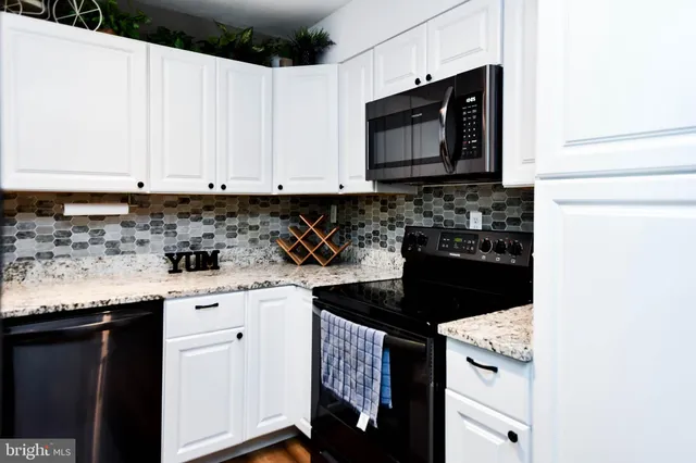 a kitchen with granite countertop white cabinets and black appliances