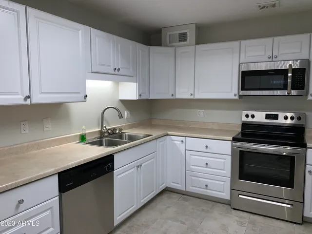 a kitchen with granite countertop white cabinets and stainless steel appliances
