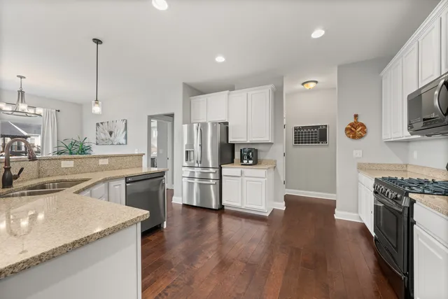 a kitchen with stainless steel appliances kitchen island granite countertop a stove top oven a sink a dining table and chairs