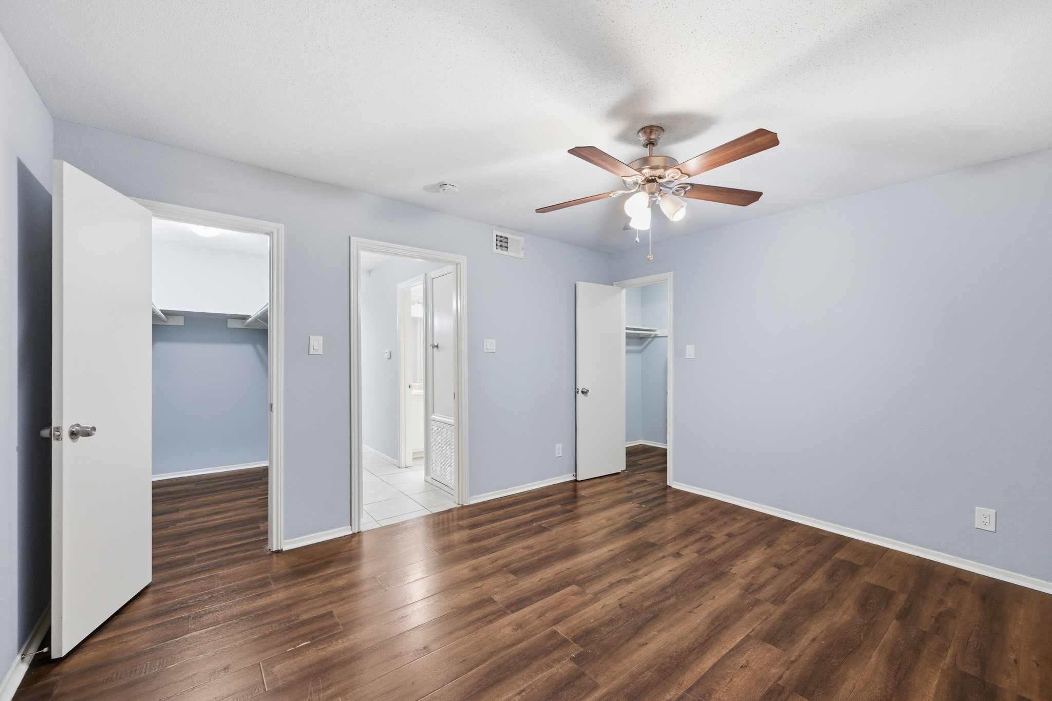 11550 Chimney Rock Road, Unit 133 Houston, TX 77035 - Photo 19 of 40 Spacious bedroom with elegant wood flooring, a ceiling fan, and ample natural light. Features dual walk-in closets and an en-suite bath for added convenience.