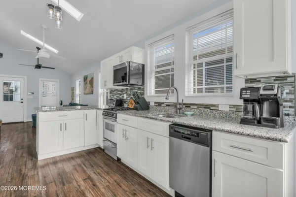 a kitchen with granite countertop cabinets stainless steel appliances a sink and a large window