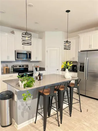 a kitchen with stainless steel appliances kitchen island granite countertop a refrigerator a stove a sink dishwasher a dining table and chairs with wooden floor