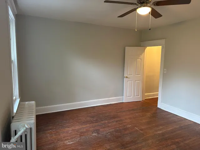 an empty room with wooden floor closet and windows
