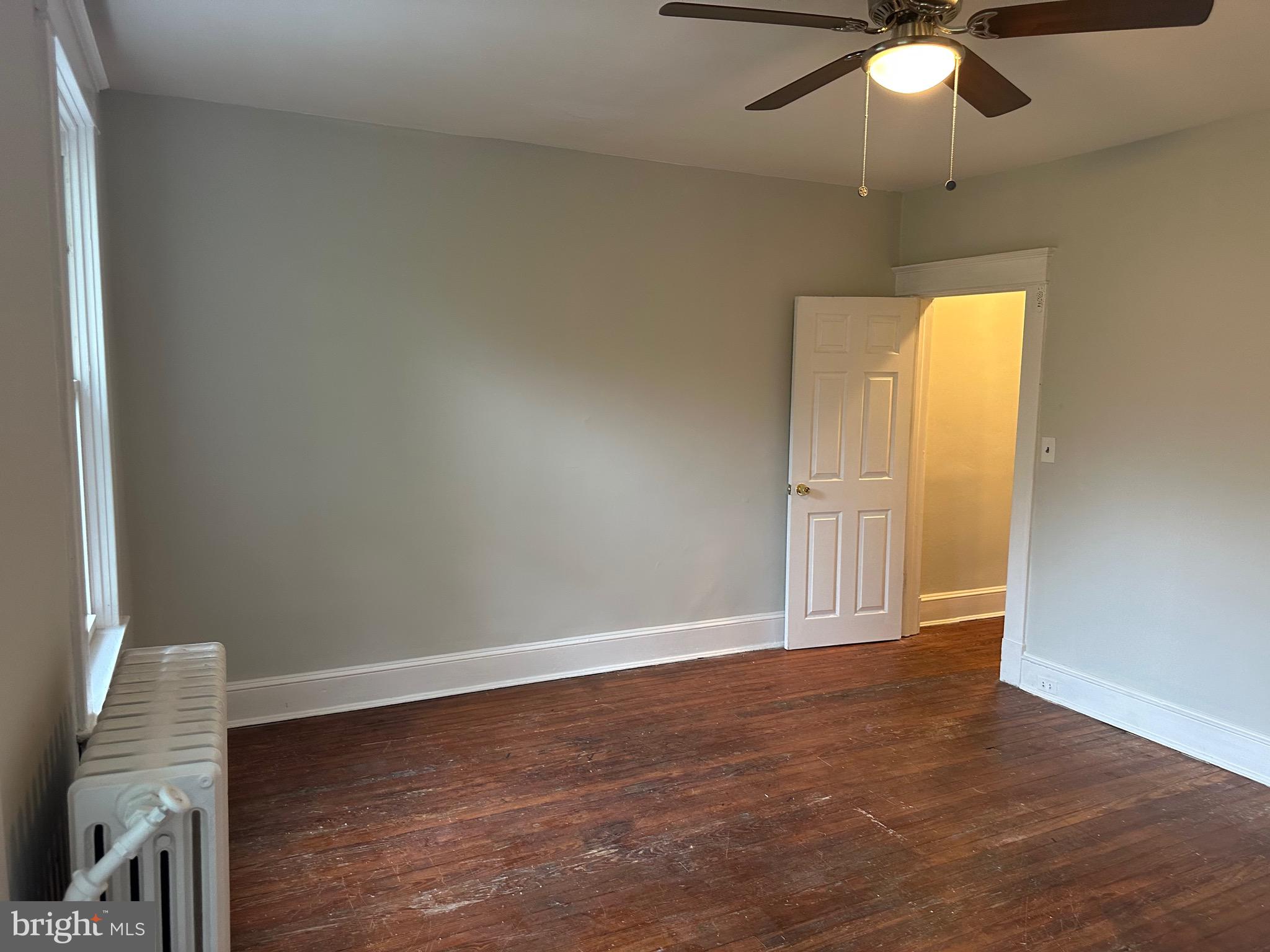 4227 Euclid Avenue, Unit B Baltimore, MD 21229 - Photo 13 of 87 an empty room with a chandelier fan and wooden floor