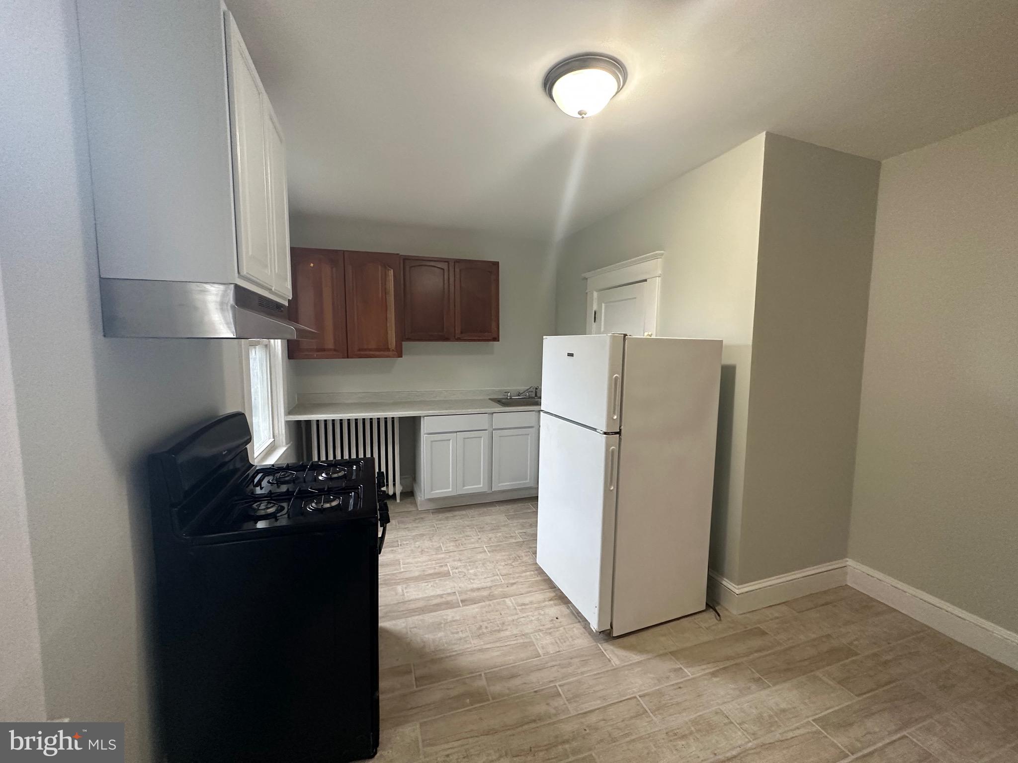 4227 Euclid Avenue, Unit B Baltimore, MD 21229 - Photo 37 of 87 a kitchen with a refrigerator a stove top oven a counter space and cabinets