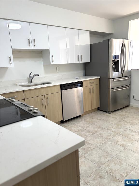 344 Prospect Avenue, Unit 9G Hackensack, NJ 07601 - Photo 12 of 16 a kitchen with stainless steel appliances a stove a sink and white cabinets