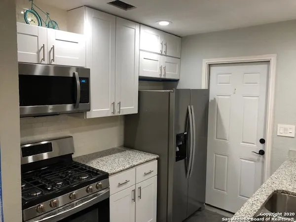 a kitchen with stainless steel appliances granite countertop a stove a sink and a refrigerator