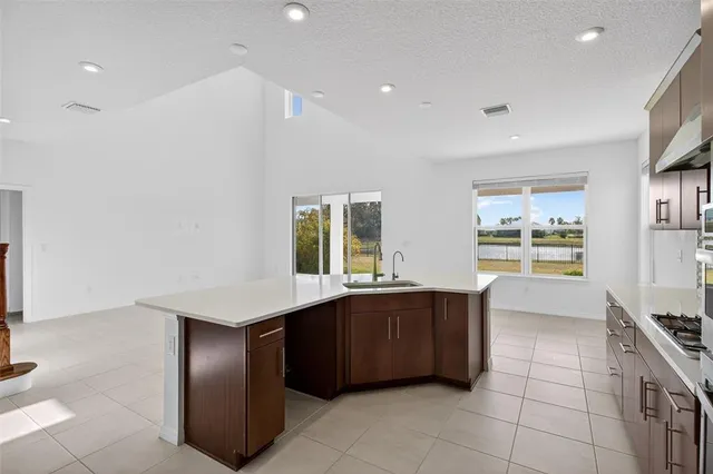 a kitchen with stainless steel appliances kitchen island granite countertop a sink and a refrigerator