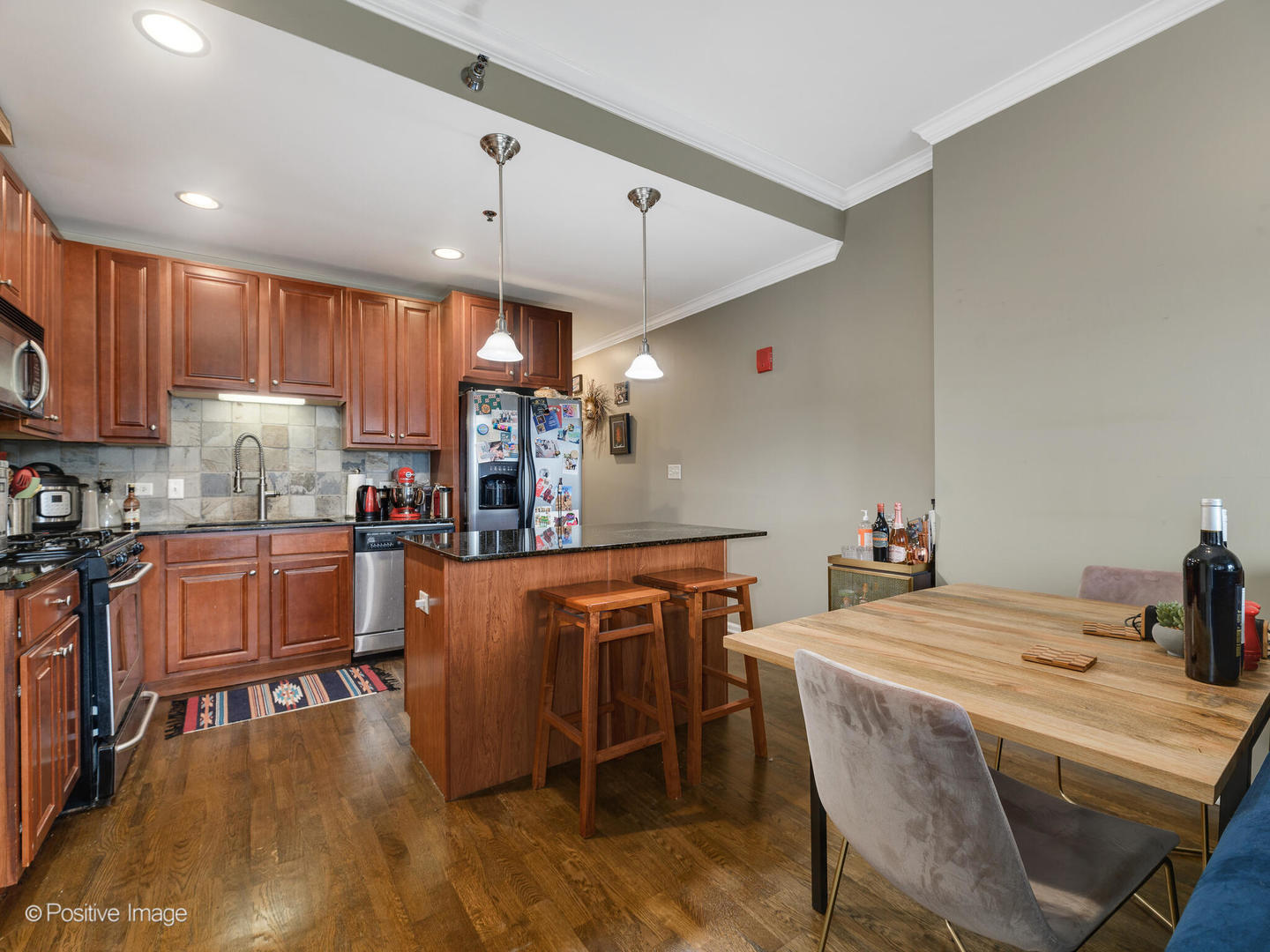 828 West Grace Street, Unit 508 Chicago, IL 60613 - Photo 7 of 15 a kitchen with stainless steel appliances kitchen island granite countertop a dining table chairs sink and white cabinets