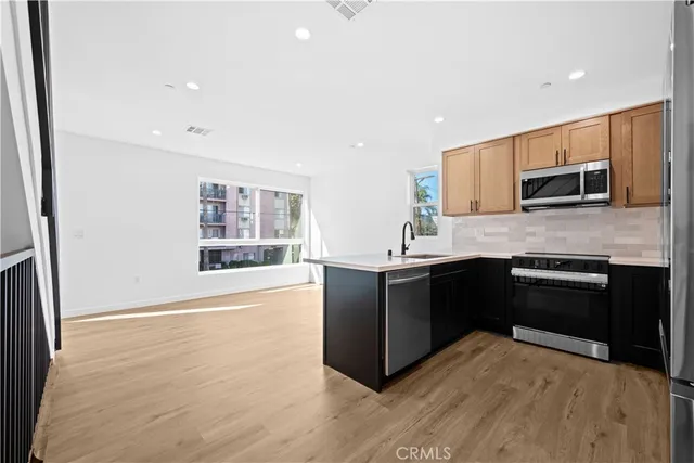 a kitchen with stainless steel appliances kitchen island granite countertop a refrigerator a stove top oven a sink and dishwasher