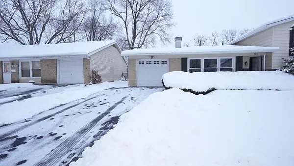 a front view of a house with a yard covered in snow