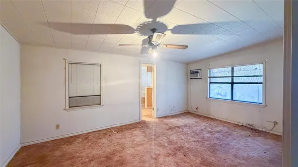 an empty room with chandelier fan and windows