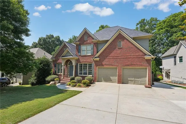 a view of a white house with a small yard and large trees
