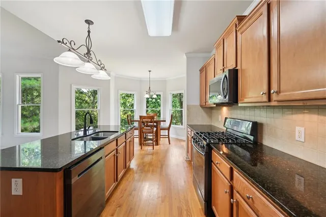 a kitchen with granite countertop a sink a counter space appliances and cabinets