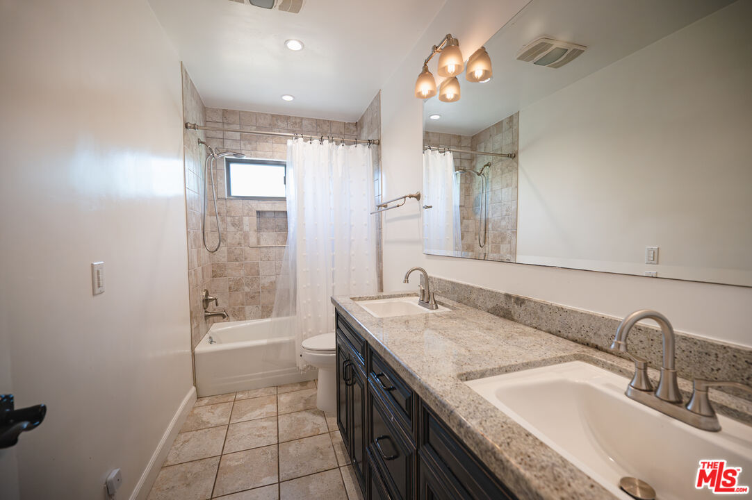 503 North Greencraig Road Los Angeles, CA 90049 - Photo 42 of 59 a bathroom with a granite countertop sink a toilet a mirror a vanity and shower