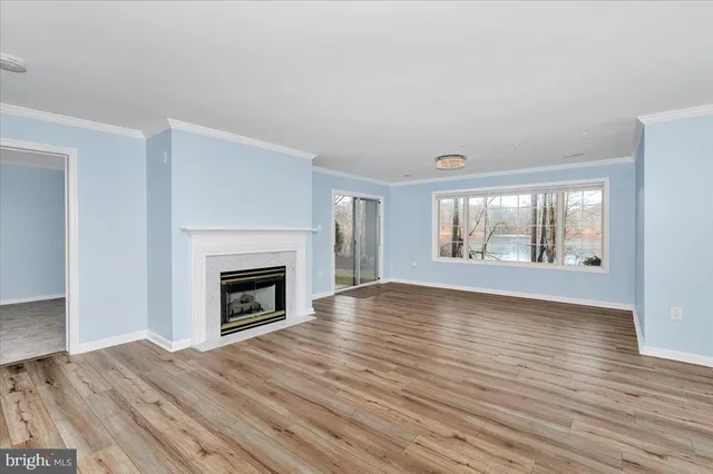 an empty room with wooden floor fireplace and windows