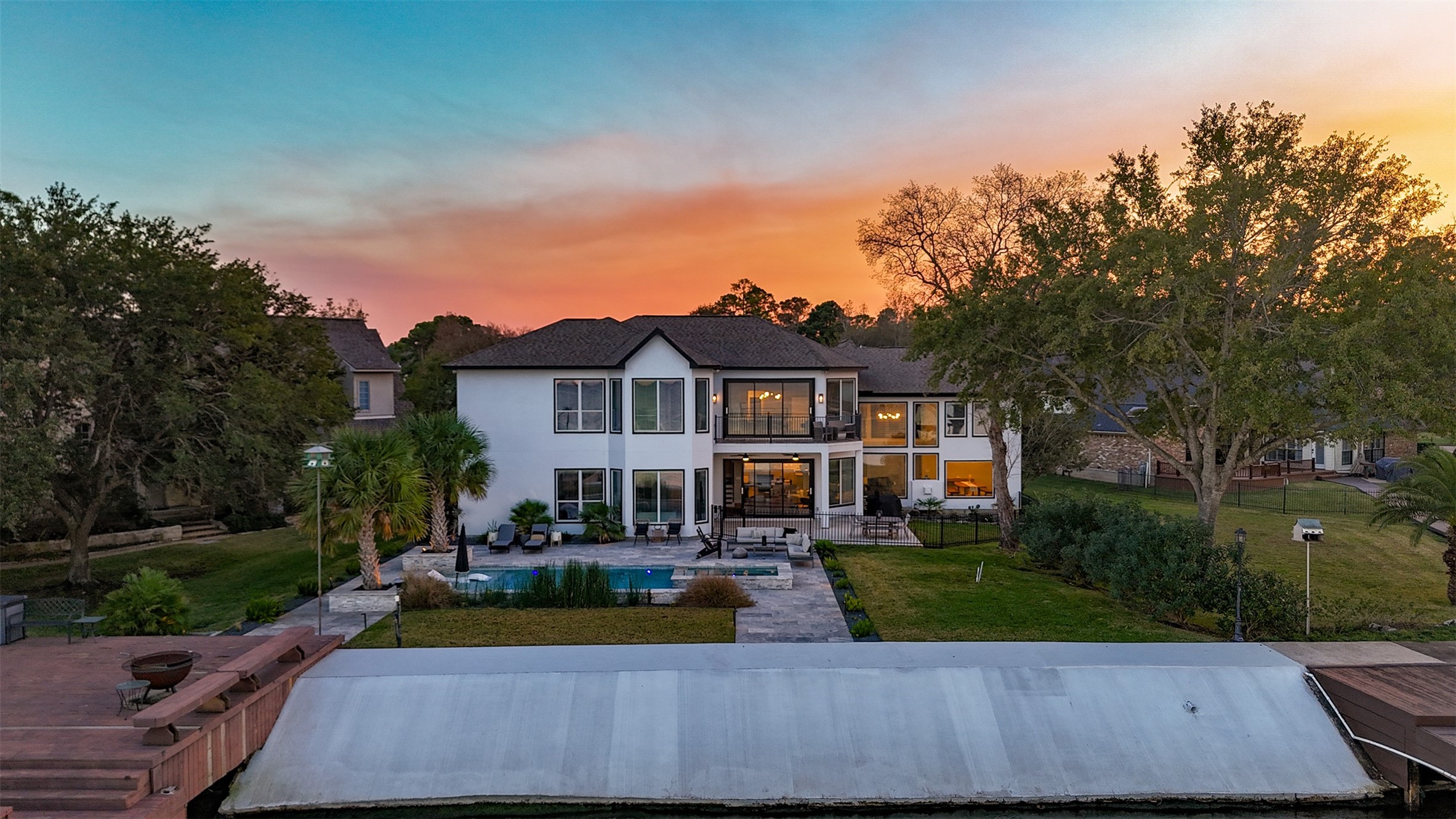 This stunning two-story home features a modern design with large windows and a spacious backyard. It includes a pool and is set against a beautiful sunset backdrop, offering a serene and luxurious living environment. Perfect for outdoor entertaining and relaxation.