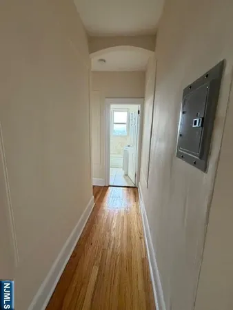 a view of a hallway with wooden floor and a bathroom