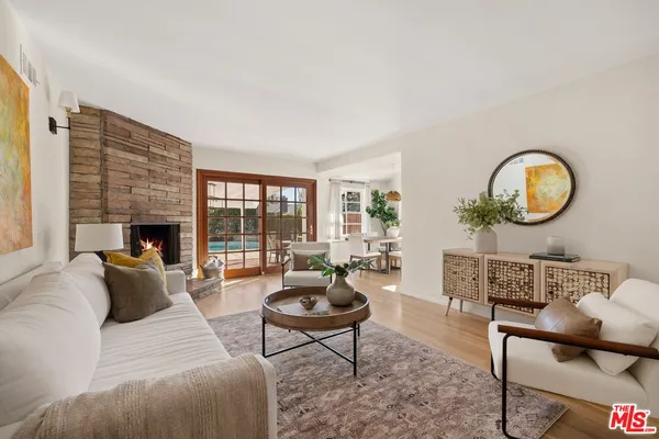 a living room with furniture a rug a fireplace and a large window