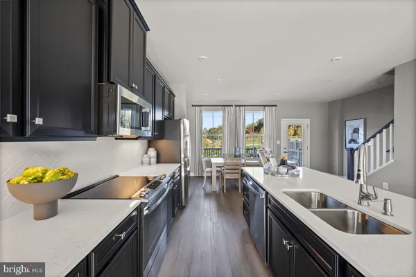 a kitchen with stainless steel appliances a sink a stove and wooden floor