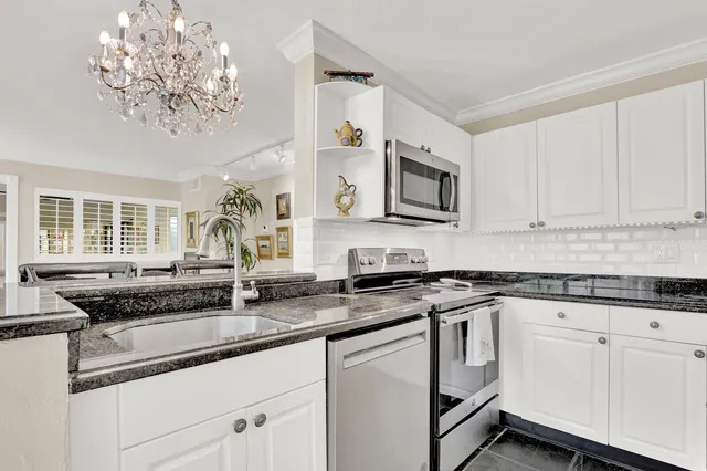 a white kitchen with granite countertop a sink a stove and cabinets
