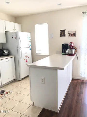 a kitchen with a refrigerator a stove top oven a counter space and wooden floor