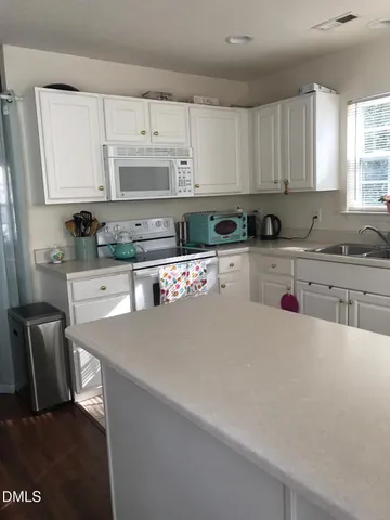 a kitchen with stainless steel appliances a sink a stove a refrigerator cabinets and a window