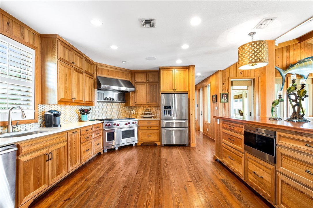 1024 Private Road East Port Aransas, TX 78373 - Photo 4 of 40 a kitchen with stainless steel appliances a stove a sink dishwasher a refrigerator and white cabinets with wooden floor