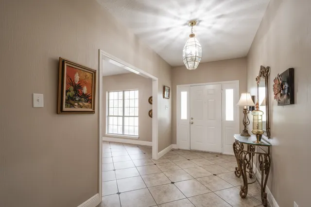 a view of a hallway with windows and chandelier fan