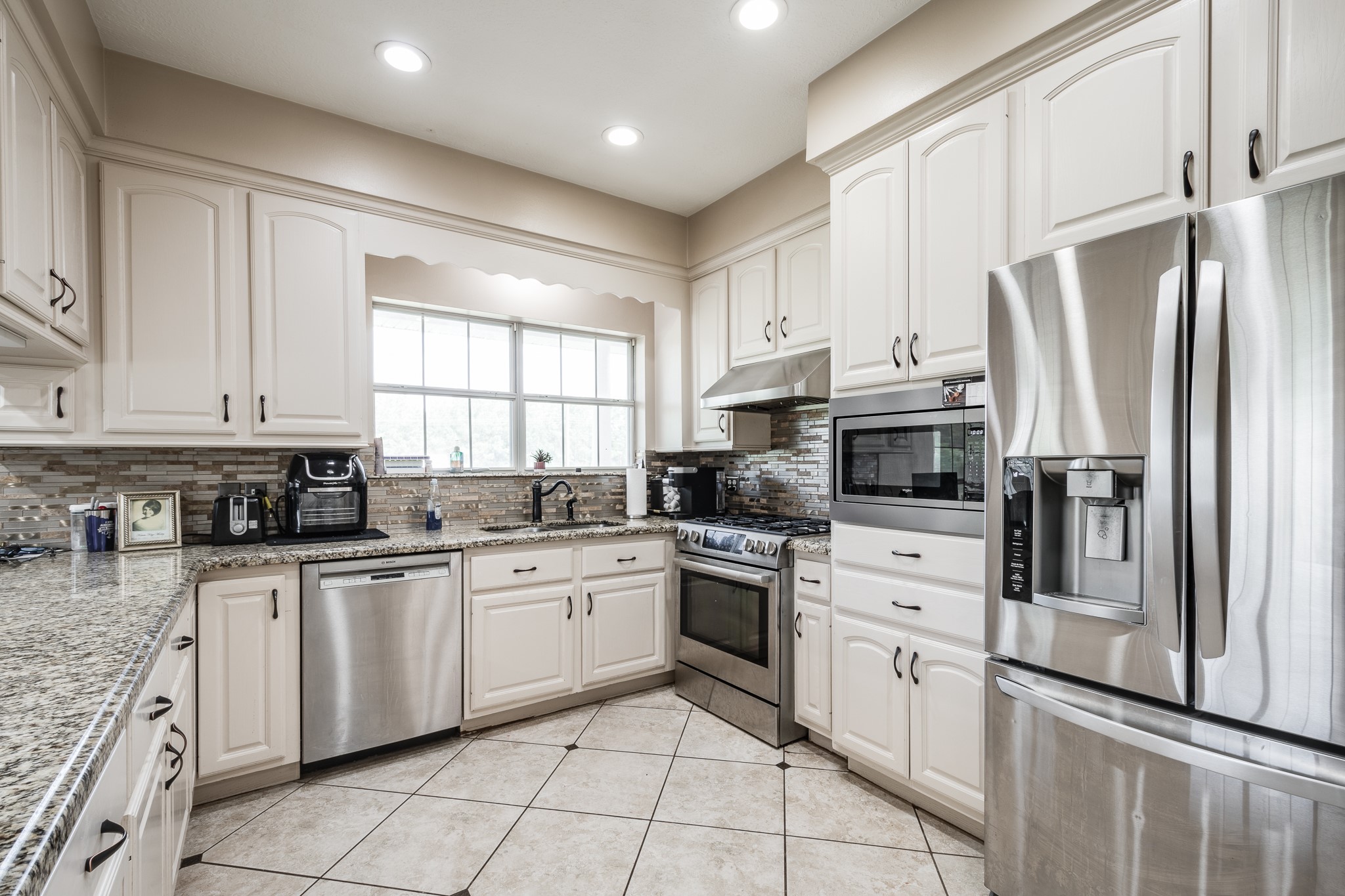 15953 1st Street Splendora, TX 77372 - Photo 10 of 23 a kitchen with white cabinets sink and stainless steel appliances