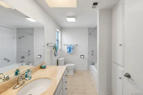 a bathroom with a granite countertop sink a toilet and shower