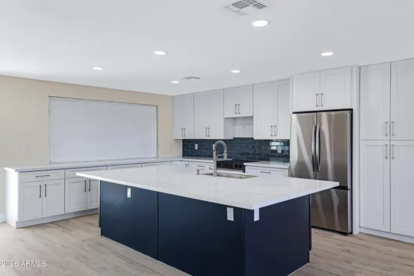a kitchen with kitchen island a sink dishwasher a refrigerator and white cabinets with wooden floor