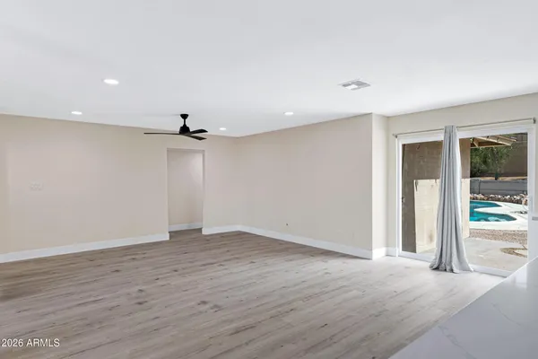 an empty room with wooden floor a ceiling fan and windows