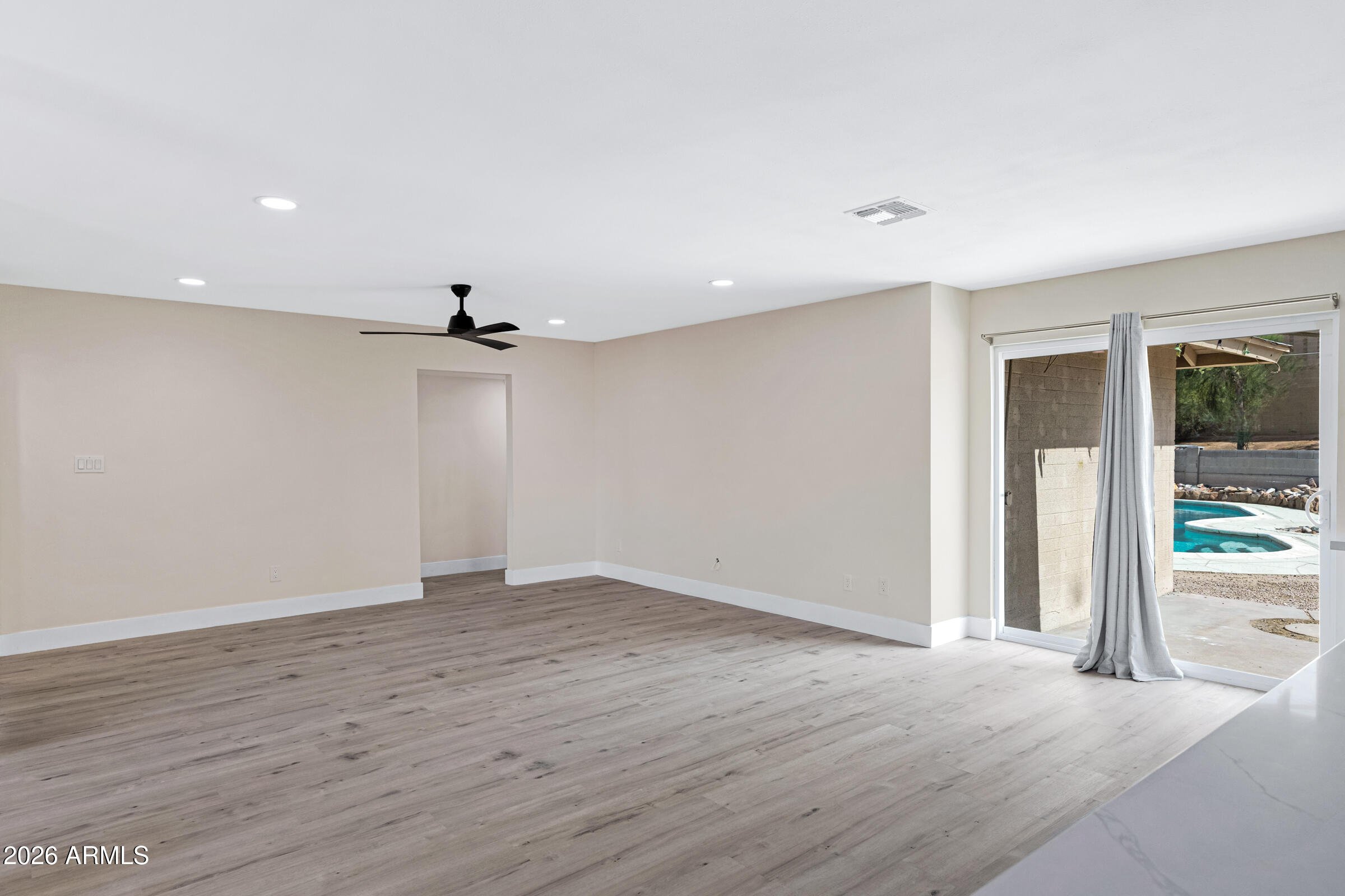 3921 South Kenneth Place Tempe, AZ 85282 - Photo 10 of 43 an empty room with wooden floor a ceiling fan and windows