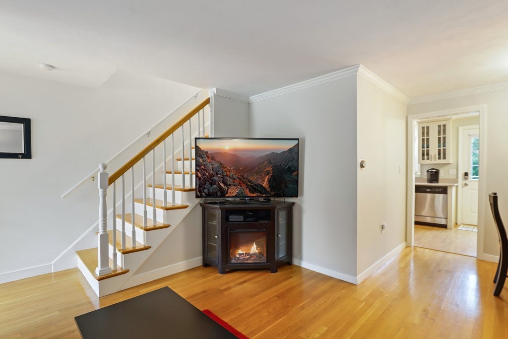 23 Clough Road, Unit 23 Dedham, MA 02026 - Photo 6 of 27 a view of an empty room with wooden floor and fireplace
