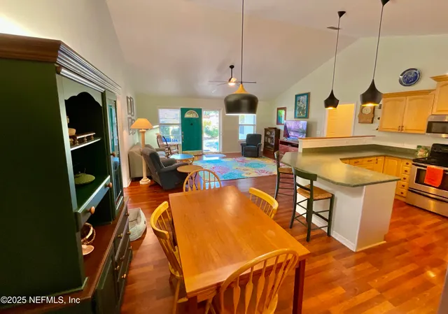 a kitchen with stainless steel appliances granite countertop a stove a refrigerator a oven a dining table and chairs with wooden floor