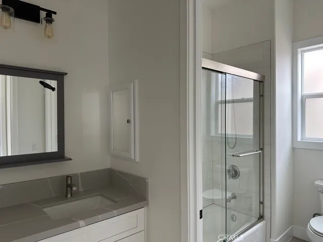 a bathroom with a granite countertop sink toilet and shower